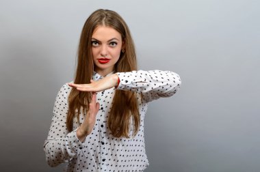 Gri duvar arka plan üzerinde izole küçük bir gülümseme gösteren zaman aşımı el hareketi ile genç kadın.