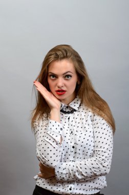 Beyaz gömlek gri bir arka plana dayanır kamera bakarak silah ile poz güzel genç kadın. 