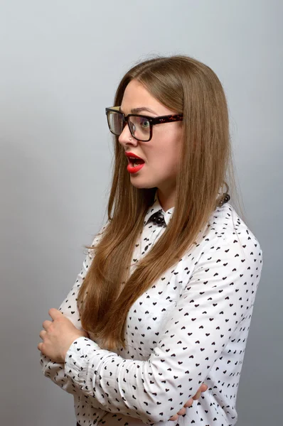 Mujer joven sorprendida en gafas sobre fondo gris —  Fotos de Stock