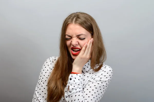 Diş ağrısı. Gri bir arka plan üzerinde güzel kadın.