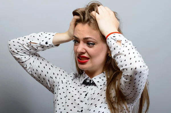 Retrato de uma jovem mulher gritando frustrada puxando o cabelo em fundo cinza — Fotografia de Stock