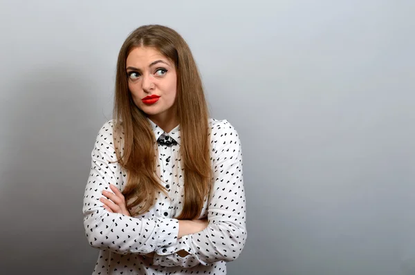 Chica con mirada condenatoria, las manos cruzadas sobre fondo gris —  Fotos de Stock