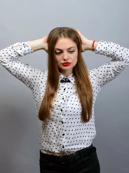 Porträt einer jungen Frau, die mit den Händen hinter dem Kopf auf grauem Hintergrund denkt — Stockfoto