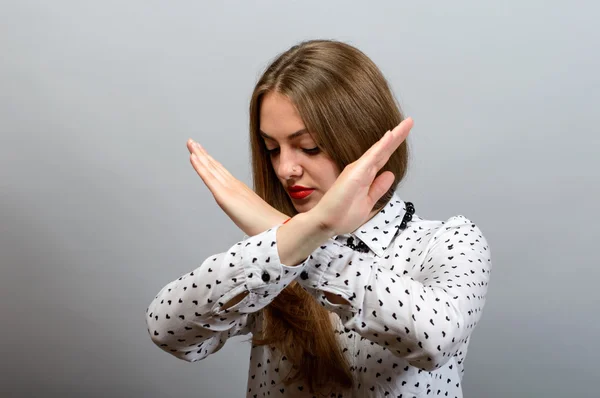 La mujer ha cruzado las manos para, no puedes. Sobre un fondo gris . — Foto de Stock