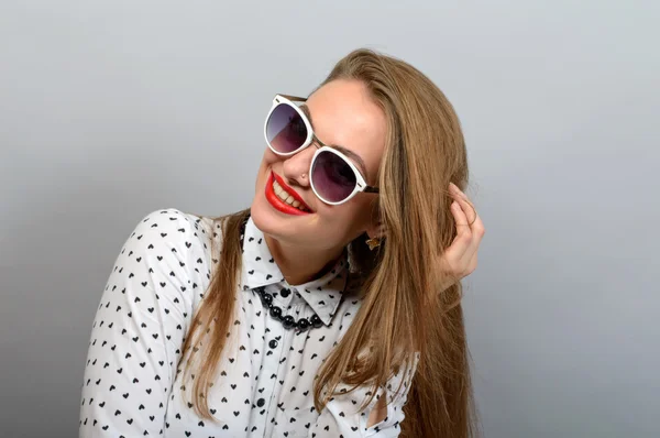 Hermosa joven feliz mujer en gafas mirando a la cámara sobre fondo gris . — Foto de Stock