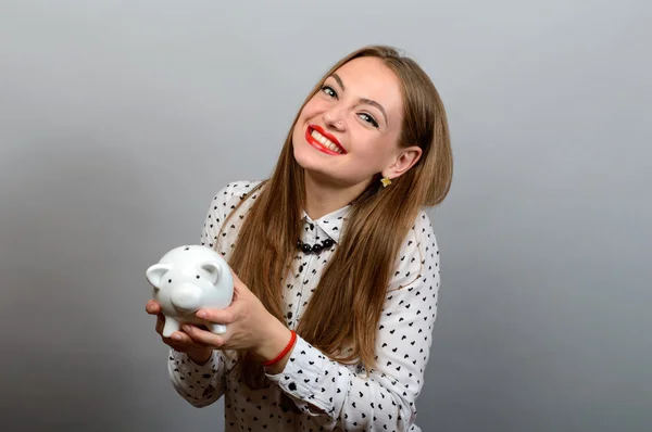 Boldog fiatal nő gazdaság érme és Piggy bank a szürke háttér — Stock Fotó