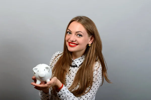 Boldog fiatal nő gazdaság érme és Piggy bank a szürke háttér — Stock Fotó