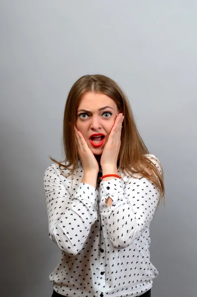 Asustada mujer conmocionada mirando a la cámara aislada sobre fondo gris de la pared . — Foto de Stock