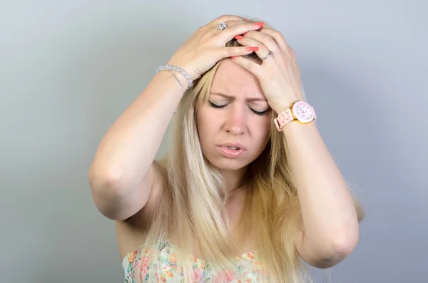 Eine junge Frau mit Kopfschmerzen am Kopf, isoliert auf grauem Hintergrund — Stockfoto