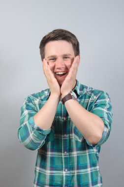 Genç ve yakışıklı bir adam gri arka planda mahsur kalmış.