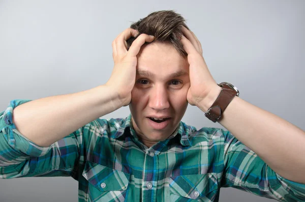 Portrait of frustrated shocked man in shirt standing against grey background — Stock Photo, Image