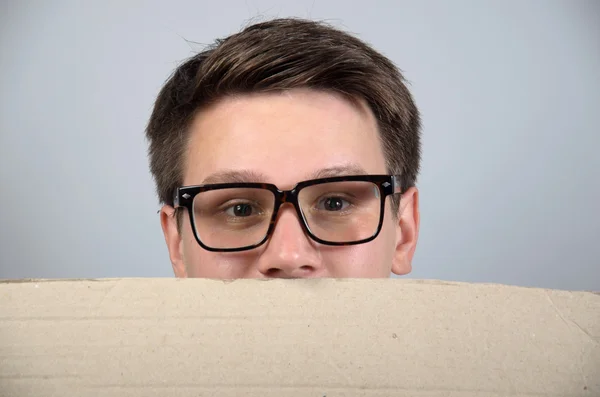 Joven sosteniendo una sábana en blanco aislado sobre gris — Foto de Stock