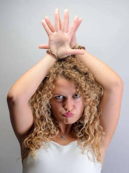 Jeune femme bouclée drôle faire des visages drôles, mettre les mains sous la tête — Photo