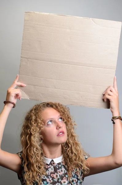 Menina segurando placa em branco no fundo cinza — Fotografia de Stock