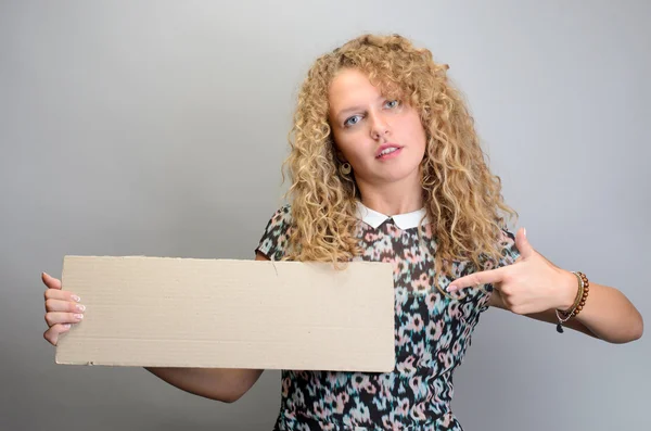 Menina segurando placa em branco no fundo cinza — Fotografia de Stock