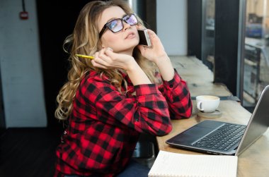 Genç kadın kafede içecekler kahve ve cep telefonda konuşurken