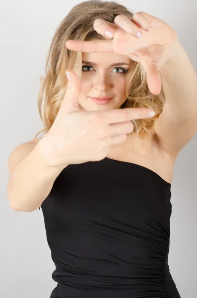 El hareketli parmak çerçevesi. Güzel genç bir kadın gri arka planda dururken kameraya ve işaret parmağına bakıyor. — Stok fotoğraf