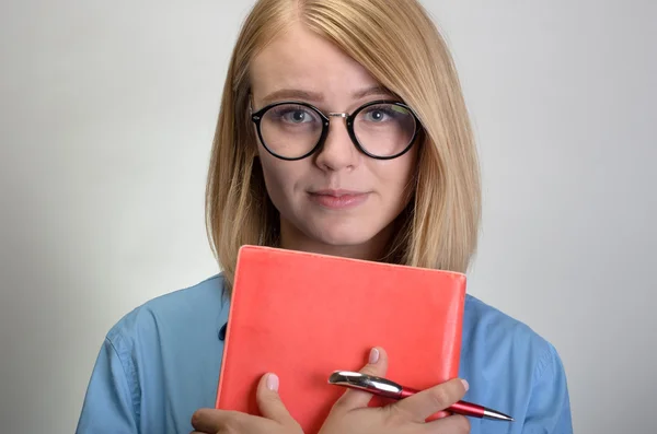 Портрет молодой улыбающейся женщины с блокнотом и ручкой — стоковое фото