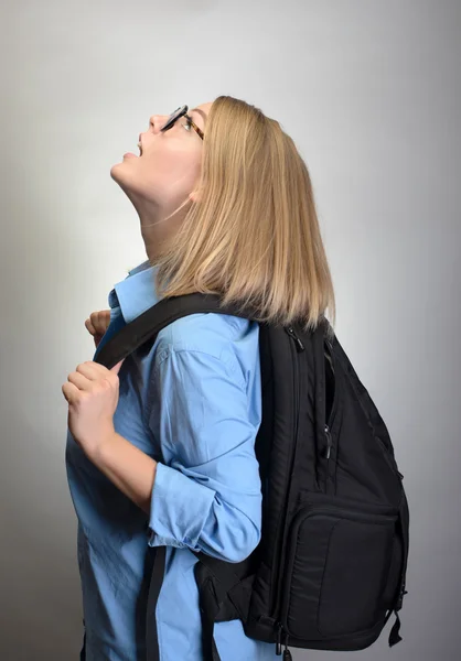 Porträt einer jungen Frau mit Rucksack vor grauem Hintergrund — Stockfoto