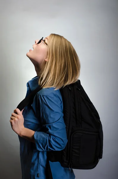 灰色の背景の上のバックパックを持つ若い女性の肖像画 — ストック写真