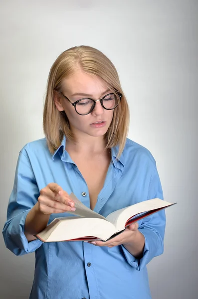 Jovem mulher bonita em óculos lendo um livro — Fotografia de Stock