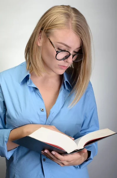 Junge hübsche Frau mit Brille liest ein Buch — Stockfoto