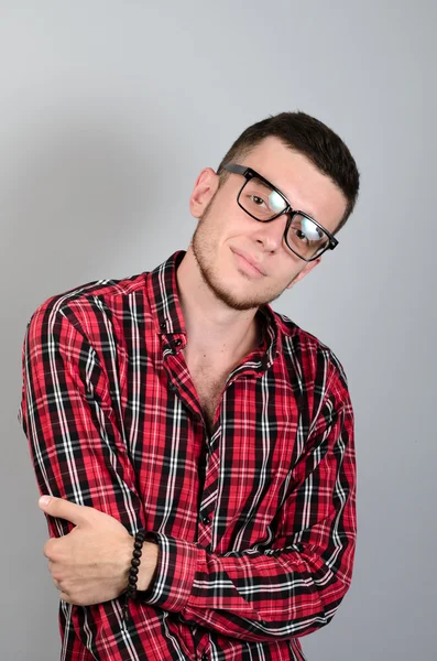 Retrato de un joven sonriendo con gafas sobre fondo gris — Foto de Stock