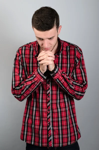 Closeup retrato jovem homem orando mãos apertadas na esperança de melhor pedir perdão ou milagre isolado fundo parede cinza . — Fotografia de Stock