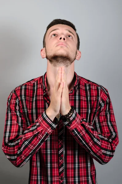 祈りの手握りしめ許しや奇跡を求めてベストを期待してクローズ アップ肖像若い男隔離灰色の壁の背景. — ストック写真