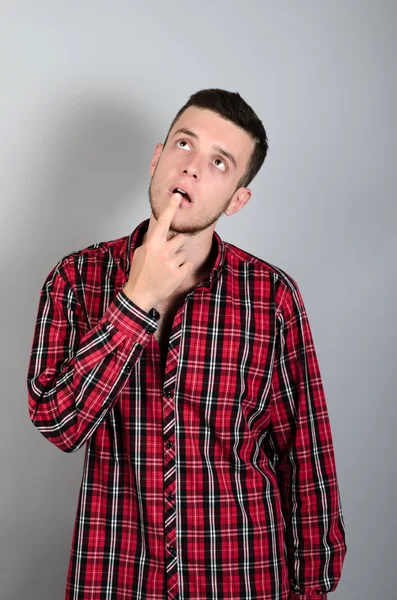 Joven guapo hombre dudando aislado sobre gris fondo —  Fotos de Stock