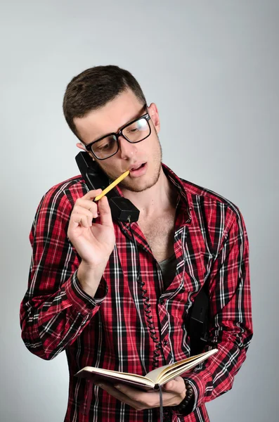 Junger Mann telefoniert am Festnetztelefon und schreibt Notizen — Stockfoto