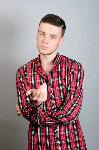 Listig man bjuda in med handen. Stående isolerad på grå bakgrund — Stockfoto