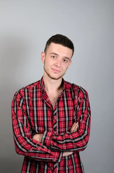 Retrato de un joven sonriendo sobre un fondo gris — Foto de Stock