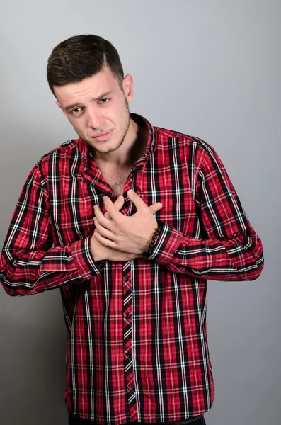 Elleri göğsünde bir ağrı kalp ahbap. Gri bir arka plan üzerinde.