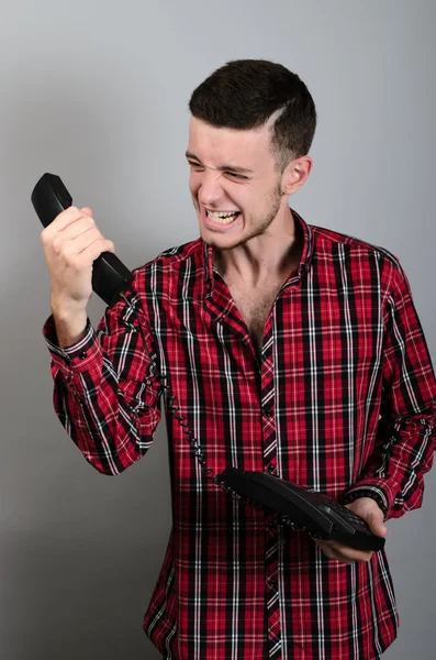 Hombre de negocios enojado gritando en el teléfono fijo en gris — Foto de Stock