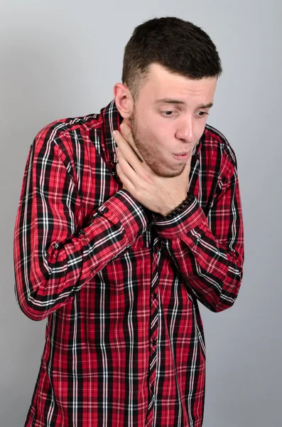 Genç adam boğmak şok hisself gri arka plan üzerinde