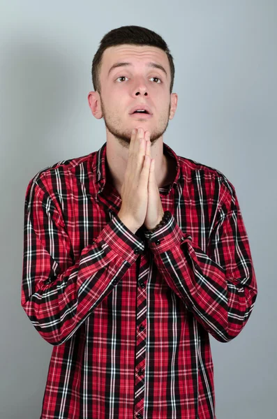 Retrato de um homem orando com os olhos fechados sobre fundo cinza — Fotografia de Stock