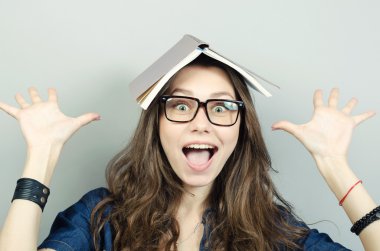 Başının üstüne gri arka plan üzerine bir kitap olan mutlu kadın