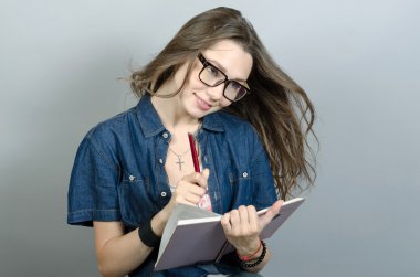 Gri zemin üzerine kalem ile defter tutan genç kadın