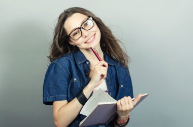 Gri zemin üzerine kalem ile defter tutan genç kadın