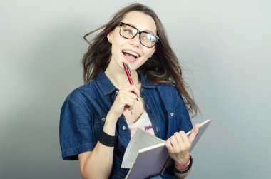 Gri zemin üzerine kalem ile defter tutan genç kadın