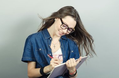 Gri zemin üzerine kalem ile defter tutan genç kadın