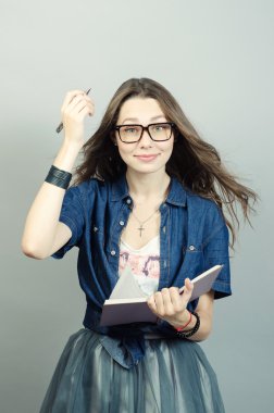 Gri zemin üzerine kalem ile defter tutan genç kadın