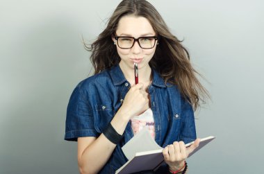 Gri zemin üzerine kalem ile defter tutan genç kadın