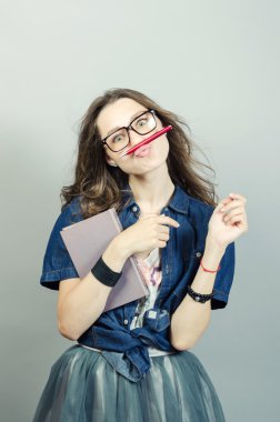 Gri zemin üzerine kalem ile defter tutan genç kadın