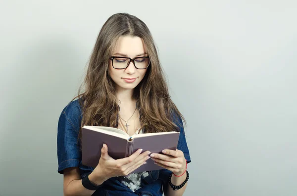 Jovem segurando livro no fundo cinza — Fotografia de Stock