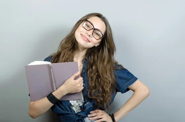 Jonge vrouw met boek over grijze achtergrond — Stockfoto