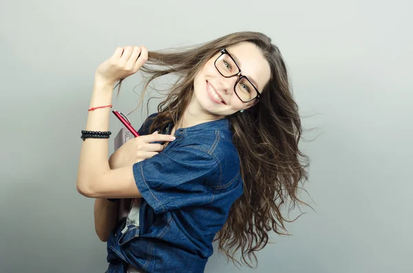 Mujer joven sosteniendo cuaderno con un bolígrafo sobre fondo gris — Foto de Stock