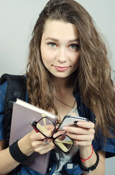 Ung kvinna med bok, glasögon, penna och mobil på grå bakgrunds — Stockfoto