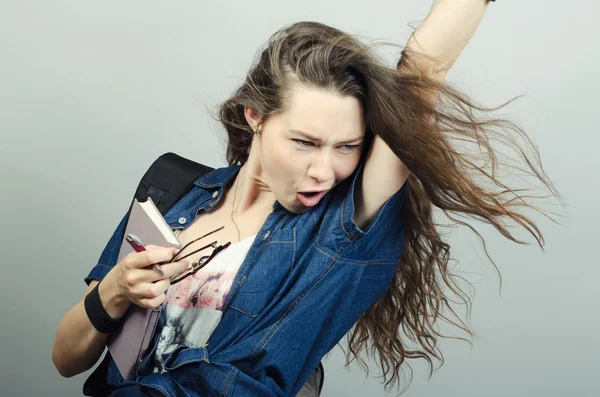 Young funny woman holding book and pulling her hair — Stock Photo, Image